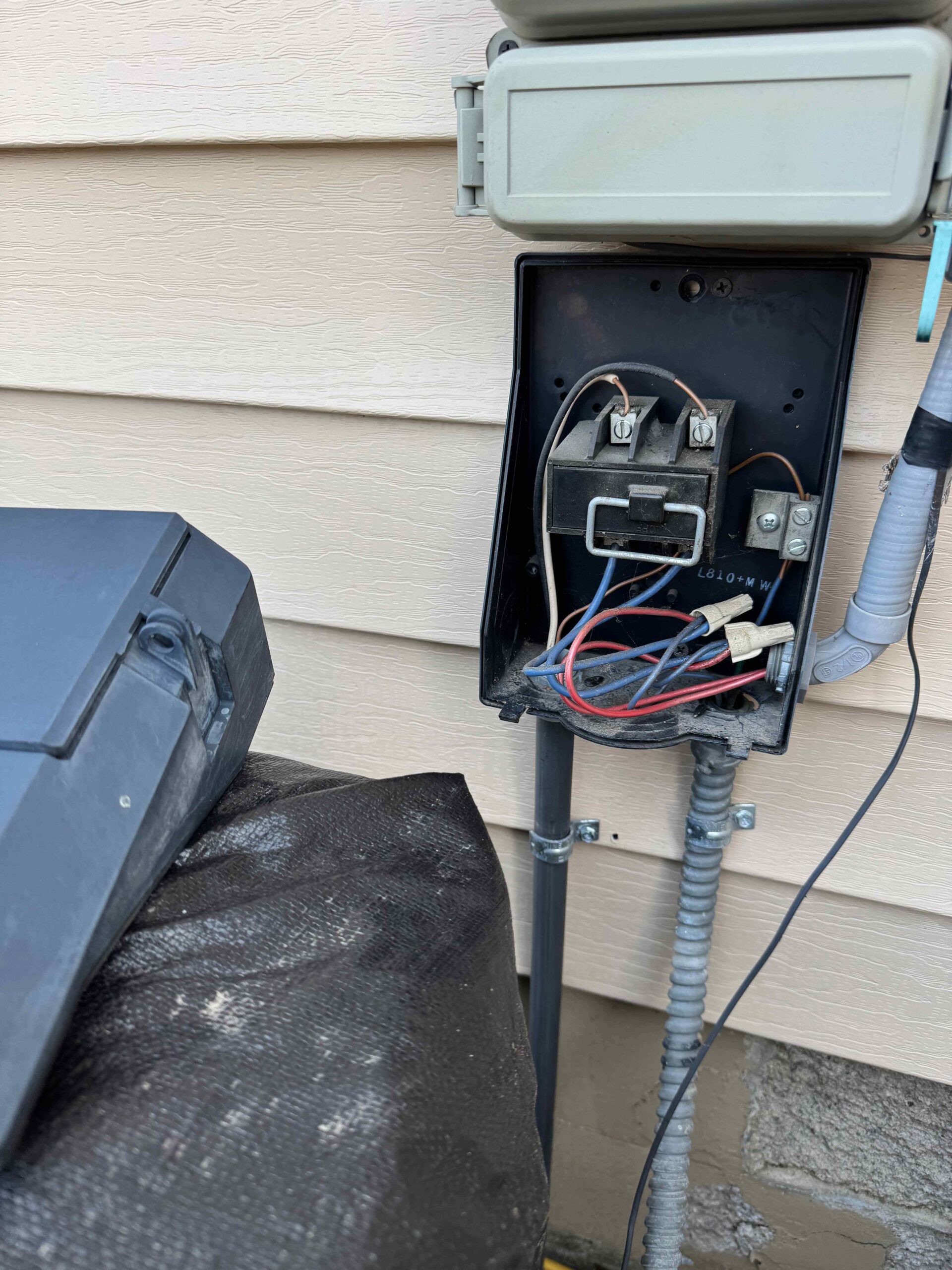 Open electrical box with exposed wires on house exterior