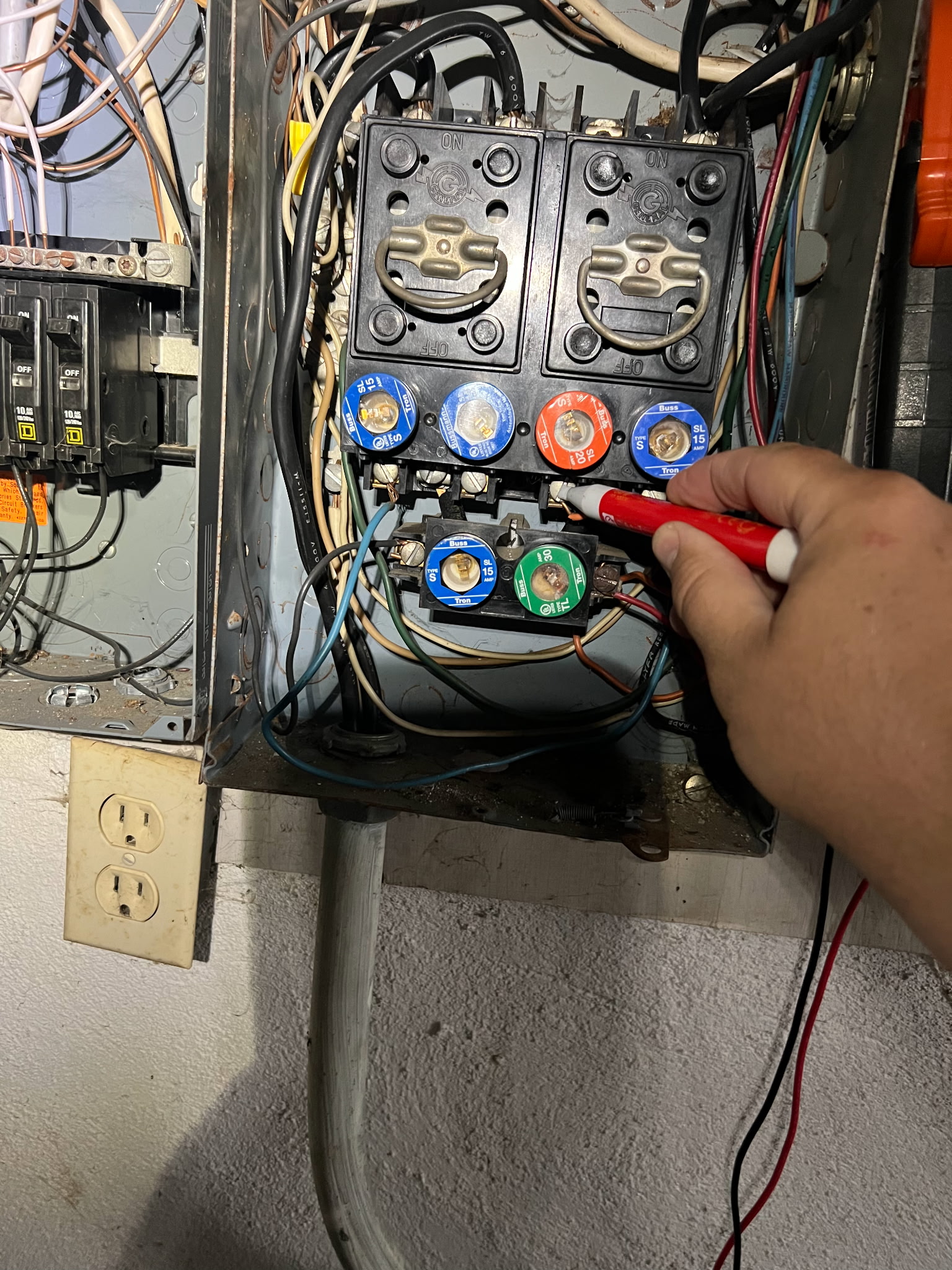 Person testing old fuse box with voltage tester tool