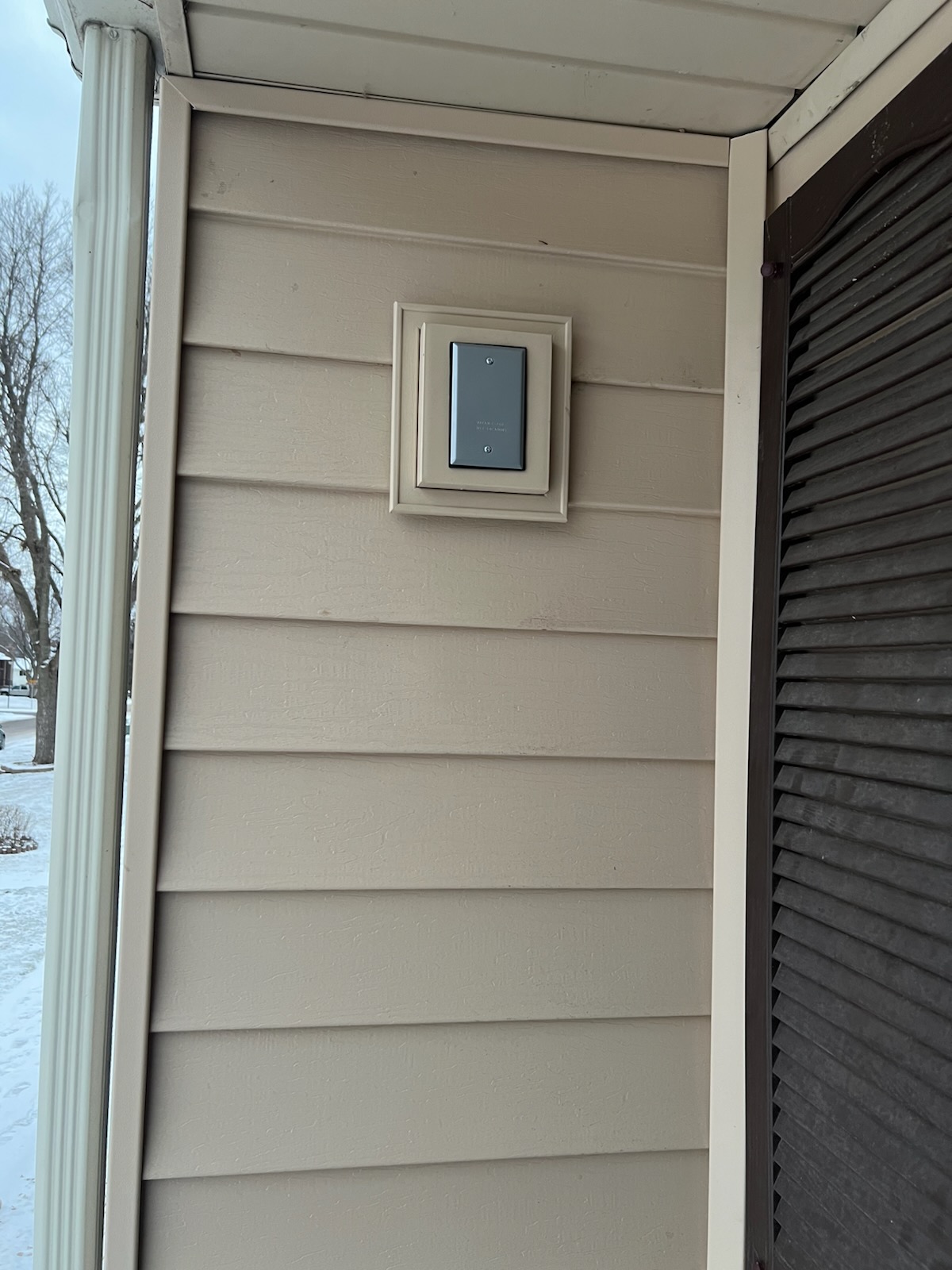 Outdoor wall with mounted electrical cover plate