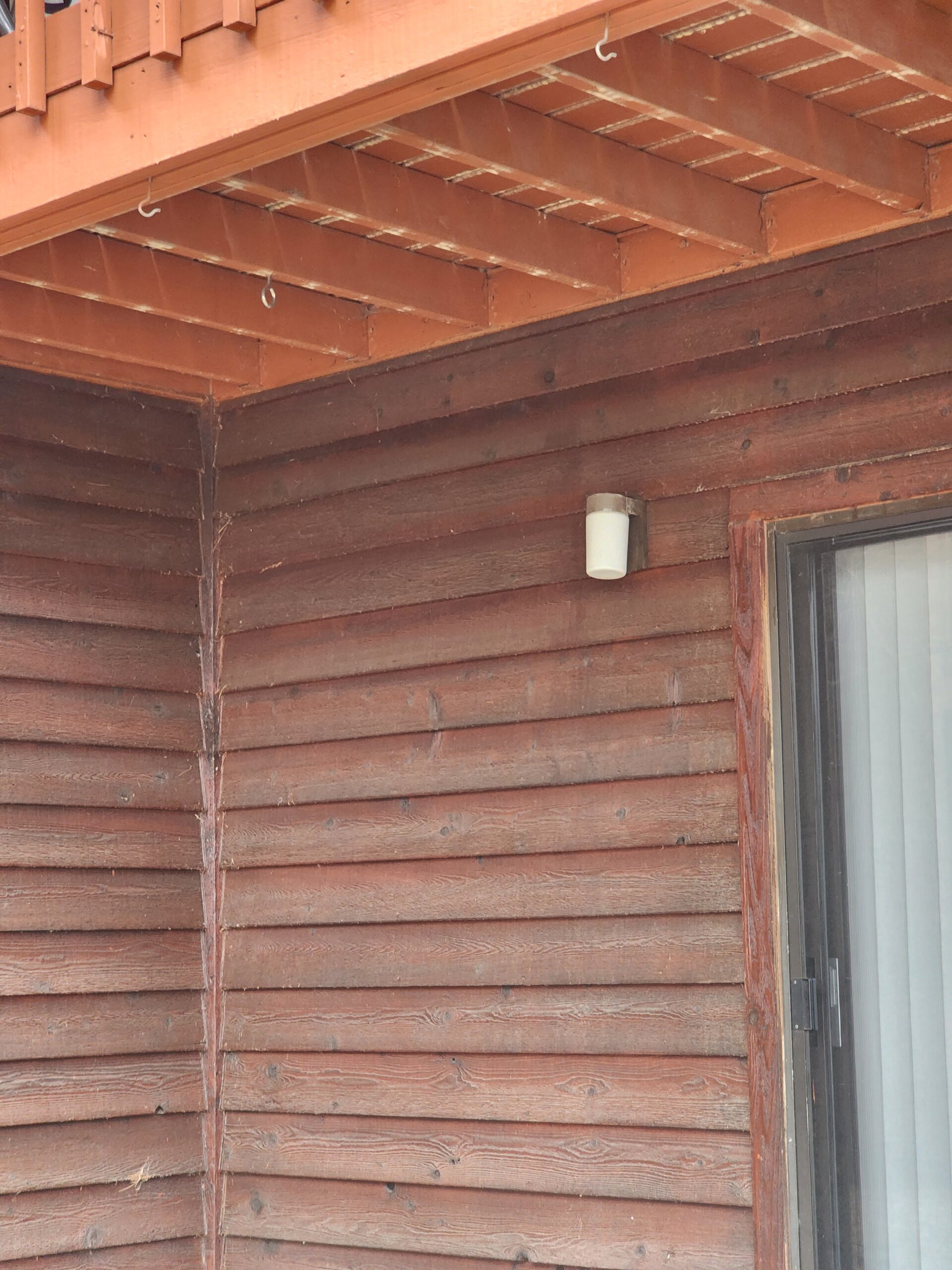 Wood cabin exterior with wall light under balcony