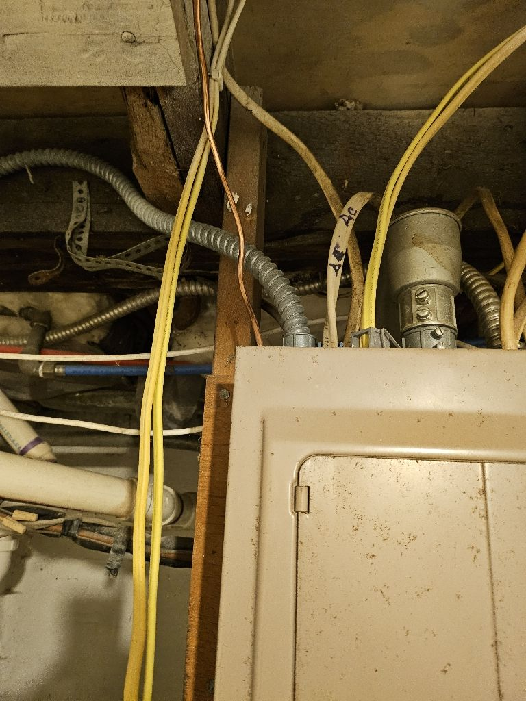 Electrical panel with yellow wires and conduit overhead